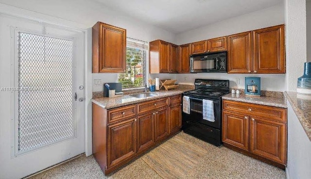 kitchen featuring black appliances, brown cabinetry, a sink, and light countertops