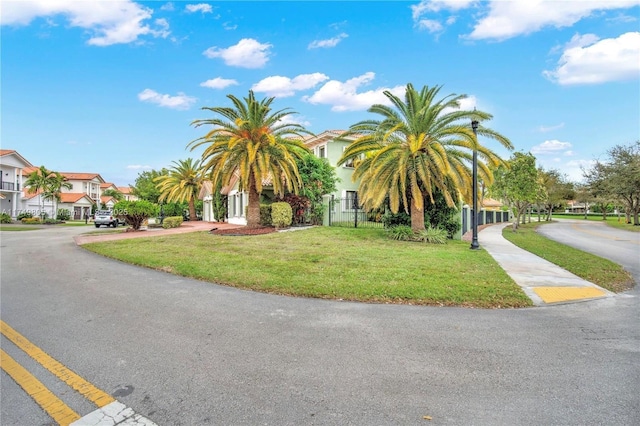 obstructed view of property featuring a front lawn, fence, and a residential view