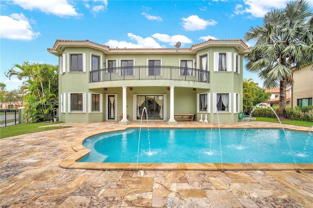 rear view of property featuring a fenced in pool, a patio area, a balcony, and stucco siding