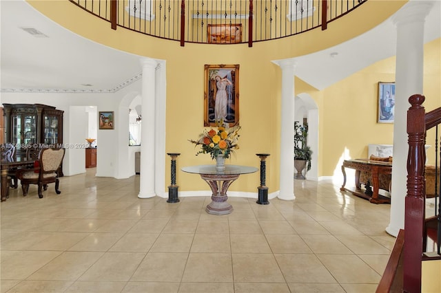 foyer with arched walkways, light tile patterned flooring, visible vents, baseboards, and decorative columns