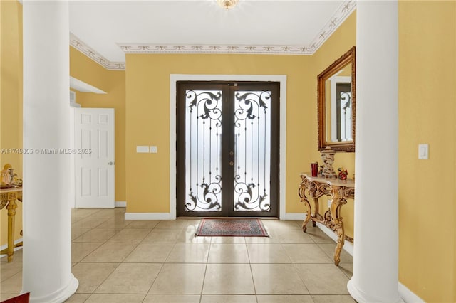 entrance foyer featuring french doors, crown molding, decorative columns, and light tile patterned floors