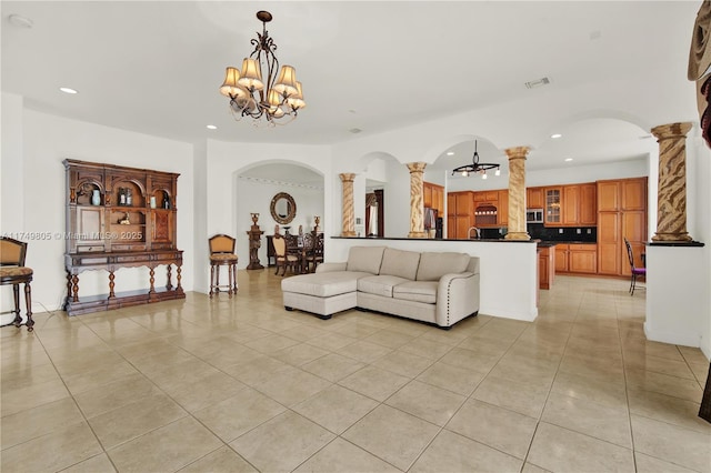 living area with a chandelier, visible vents, ornate columns, and light tile patterned floors