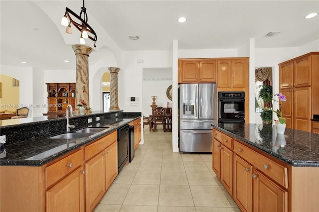 kitchen with a center island, a sink, black appliances, dark stone counters, and ornate columns