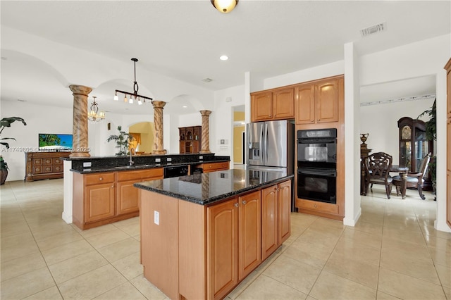 kitchen with black appliances, a center island, visible vents, and ornate columns