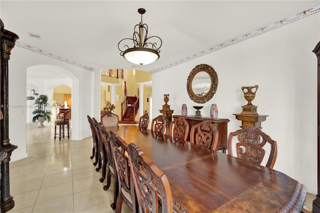 dining area with light tile patterned floors, visible vents, stairway, and arched walkways