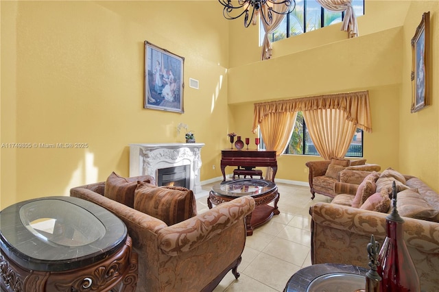 living area with a warm lit fireplace, light tile patterned floors, a notable chandelier, a towering ceiling, and visible vents