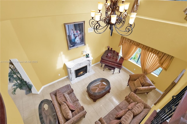 tiled living area featuring an inviting chandelier, baseboards, and a glass covered fireplace