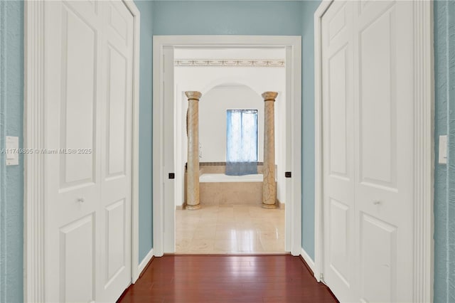 hall with arched walkways and dark wood finished floors