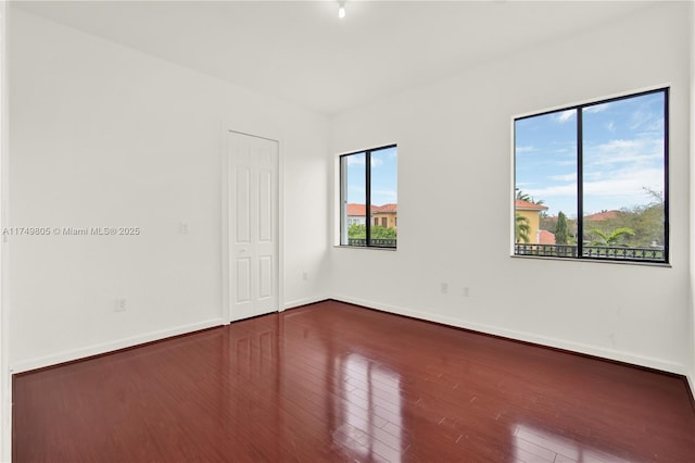 spare room with hardwood / wood-style floors and baseboards