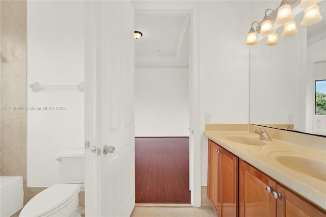 full bathroom with double vanity, a bathing tub, a sink, and toilet