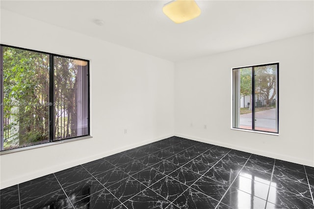 spare room with marble finish floor and baseboards