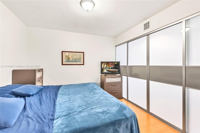 bedroom featuring light wood-type flooring, visible vents, and a closet