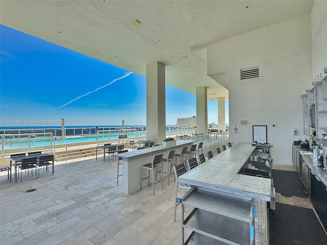 view of patio / terrace featuring a water view, visible vents, and outdoor wet bar