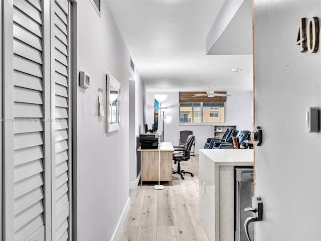 office space featuring light wood finished floors, visible vents, baseboards, and a ceiling fan