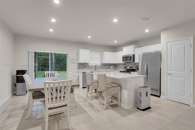 3705 Bennington Ln, Fort Pierce, FL 34981 - kitchen featuring appliances with stainless steel finishes, a center island, light countertops, tasteful backsplash, and white cabinets