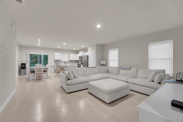 living room featuring light tile patterned floors, baseboards, and recessed lighting