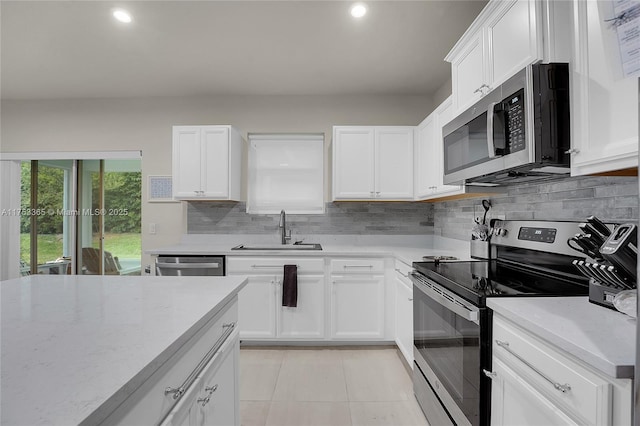 kitchen featuring white cabinets, appliances with stainless steel finishes, backsplash, and a sink