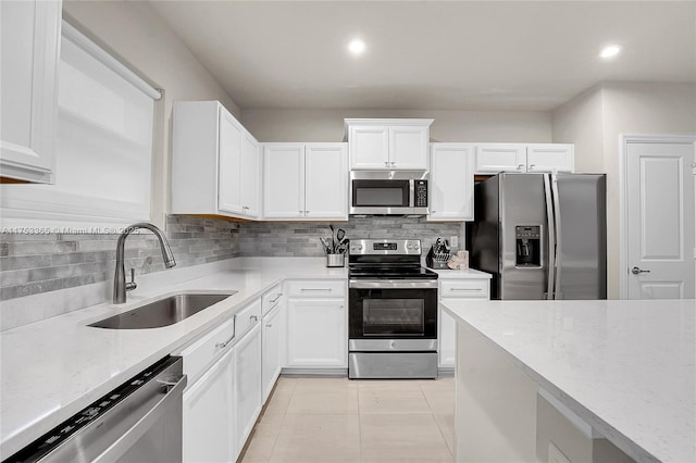 kitchen featuring light tile patterned floors, a sink, white cabinets, appliances with stainless steel finishes, and tasteful backsplash