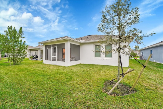 back of property featuring a lawn, a sunroom, and stucco siding