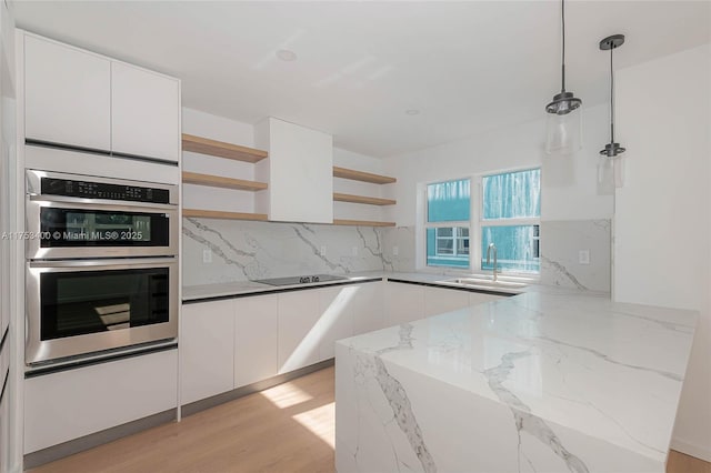 kitchen featuring a sink, double oven, open shelves, and white cabinets