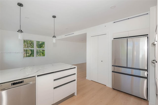 kitchen with light stone counters, light wood-style floors, white cabinets, appliances with stainless steel finishes, and pendant lighting