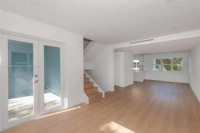 spare room featuring light wood-style flooring, stairs, and french doors