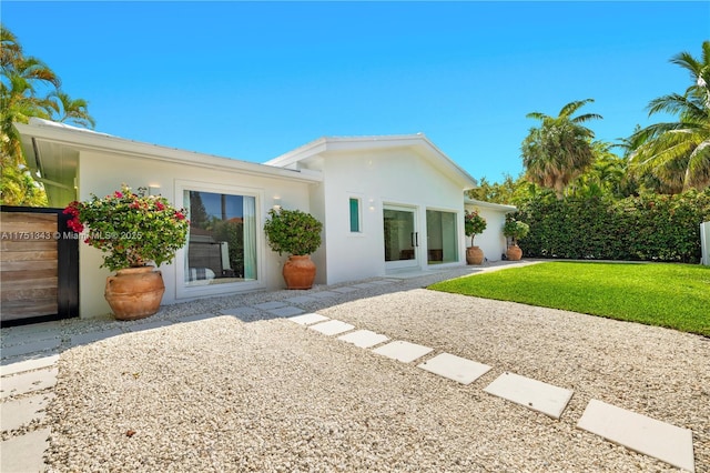 back of property featuring a lawn, a patio, and stucco siding