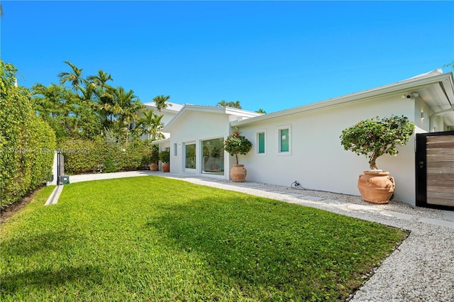 back of property with a yard, fence, and stucco siding