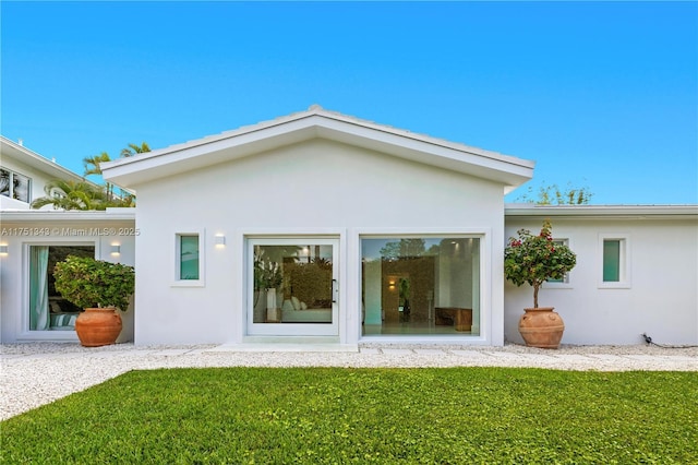 rear view of property with a yard and stucco siding