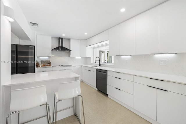 kitchen featuring visible vents, wall chimney exhaust hood, modern cabinets, a breakfast bar, and black appliances