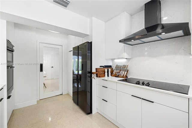 kitchen with visible vents, white cabinets, wall chimney range hood, light countertops, and black appliances