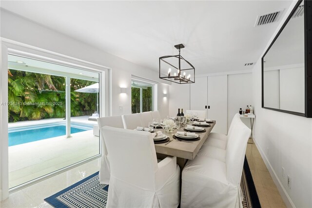 dining room with baseboards, light tile patterned floors, visible vents, and an inviting chandelier