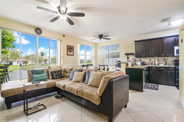 living room with ceiling fan, visible vents, a textured ceiling, and light tile patterned flooring