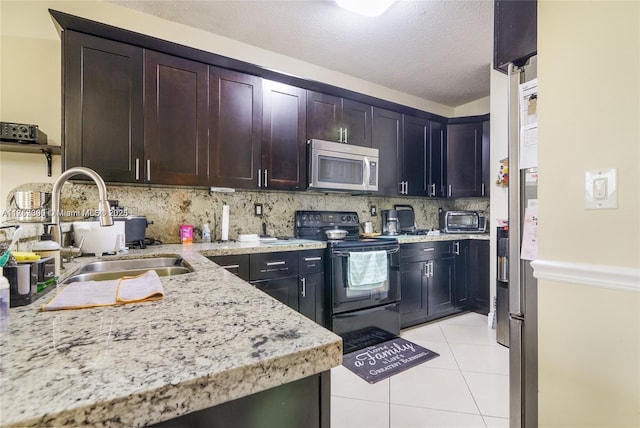 kitchen with light tile patterned floors, decorative backsplash, stainless steel microwave, black electric range, and a sink