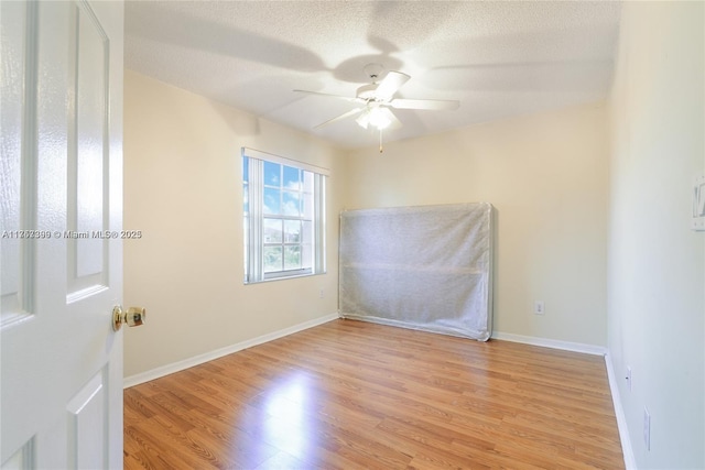 spare room with light wood-type flooring, ceiling fan, a textured ceiling, and baseboards