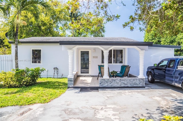 view of front of home with a front lawn, fence, a porch, and stucco siding