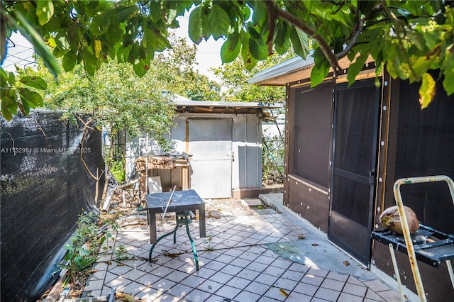 view of patio featuring a shed, fence, and an outdoor structure