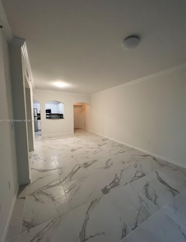 unfurnished room with ornamental molding, arched walkways, marble finish floor, and baseboards