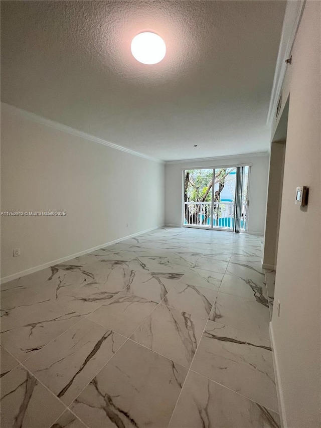 spare room featuring marble finish floor, crown molding, a textured ceiling, and baseboards