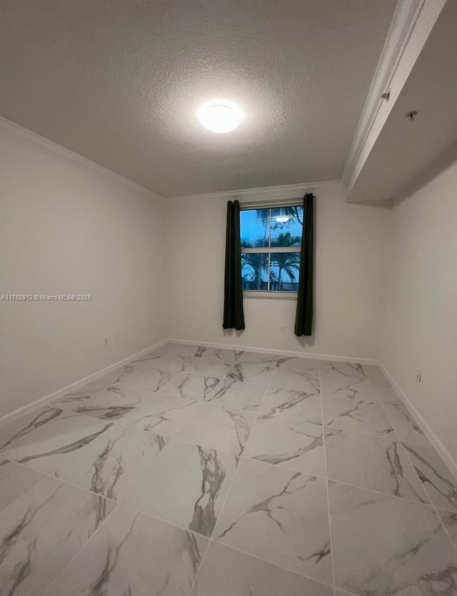 spare room featuring marble finish floor, crown molding, a textured ceiling, and baseboards