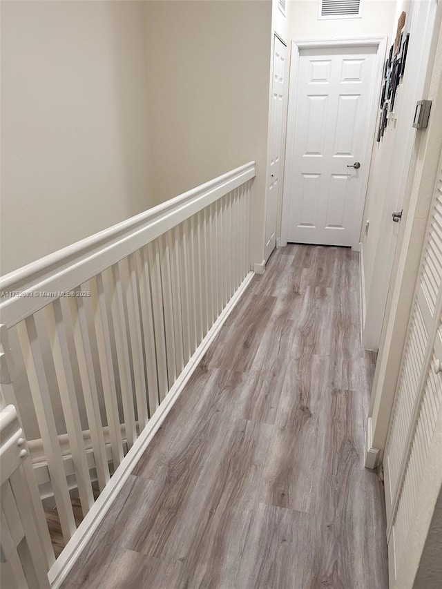 corridor featuring visible vents, baseboards, and wood finished floors