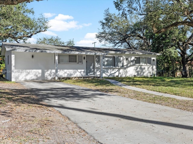 view of front of home with stucco siding, a front lawn, and driveway