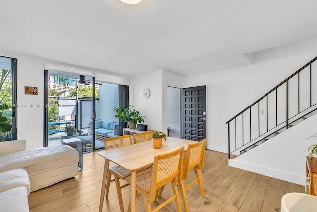 dining space with light wood-type flooring and stairs