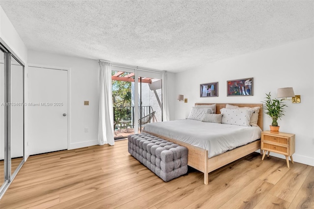 bedroom featuring access to exterior, light wood-style flooring, baseboards, and a textured ceiling