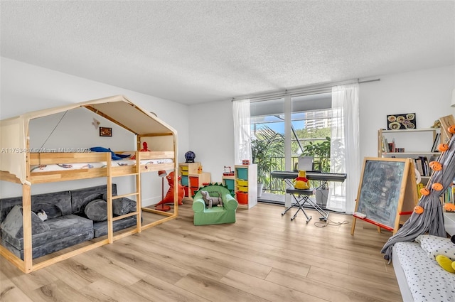 bedroom with a textured ceiling, wood finished floors, and floor to ceiling windows