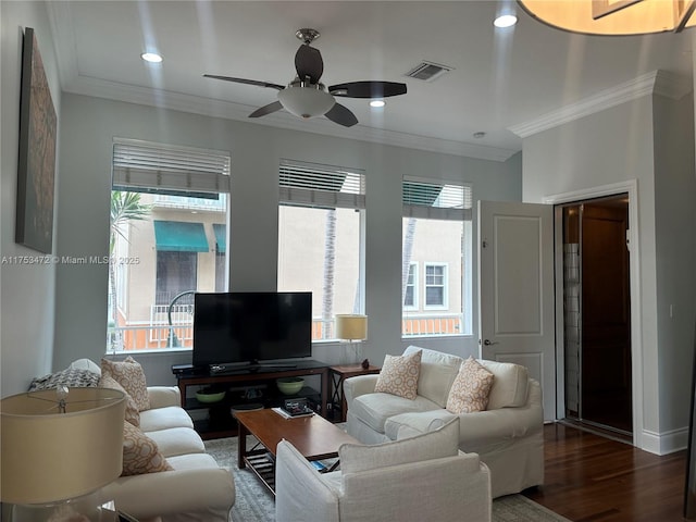 living area with ornamental molding, wood finished floors, visible vents, and a ceiling fan