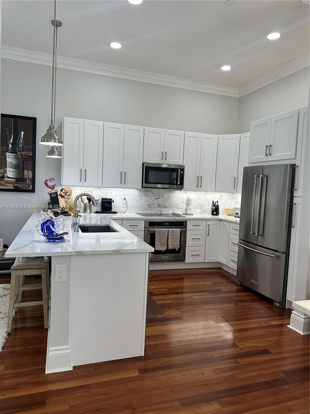 kitchen with appliances with stainless steel finishes, dark wood-style flooring, a sink, and decorative backsplash