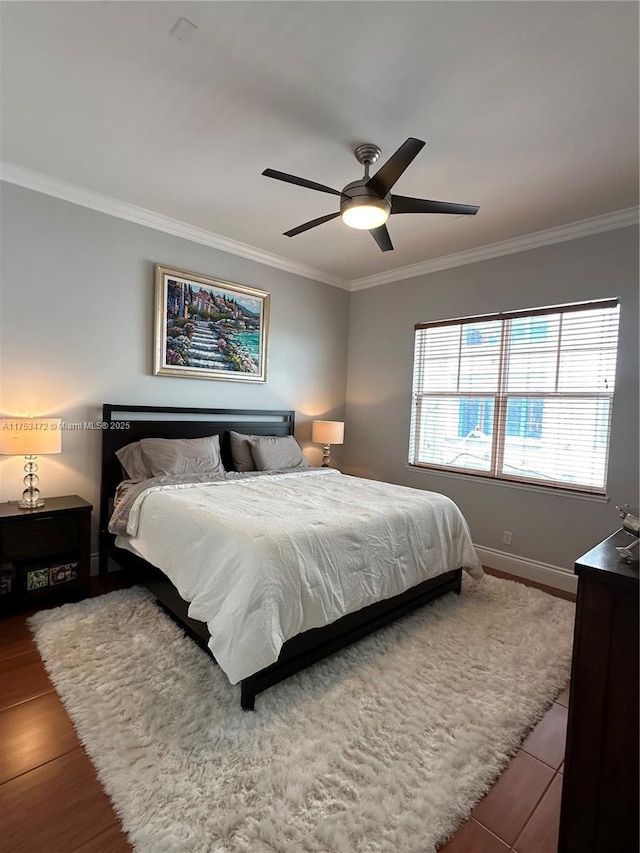 bedroom with ornamental molding, a ceiling fan, baseboards, and wood finished floors