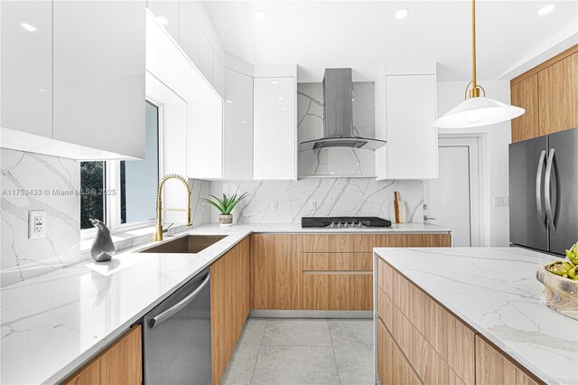 kitchen with wall chimney exhaust hood, modern cabinets, a sink, and stainless steel appliances