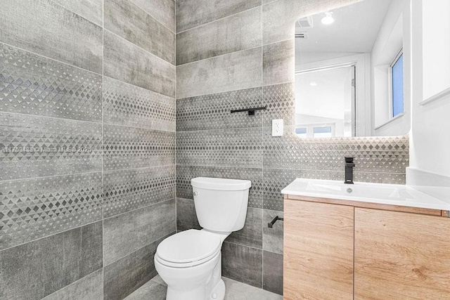 half bathroom with tile walls, toilet, and vanity